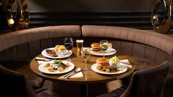 A round table with plates of food, glasses of wine, and a bowl of salad in a restaurant setting.