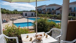 A poolside area with a table, chairs, and a view of a swimming pool.