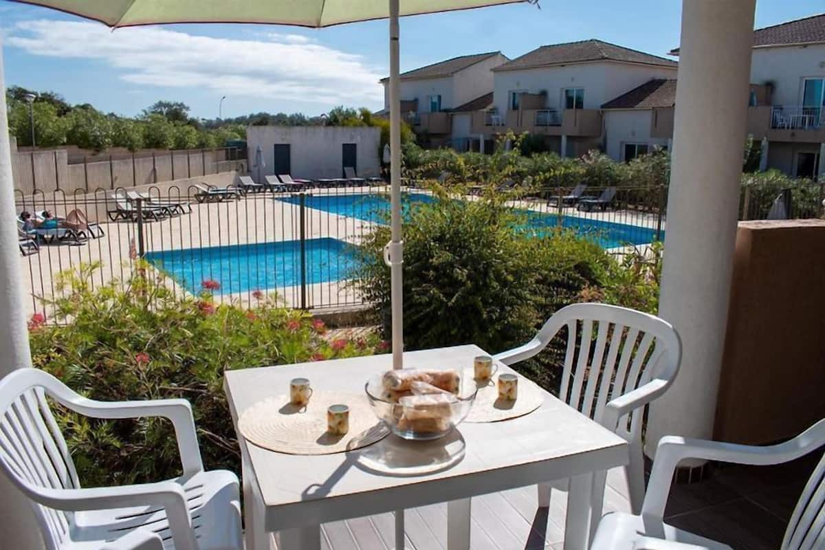 Un espace aménagé au bord de la piscine, avec une table, des chaises et une vue sur la piscine.