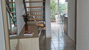 A modern kitchen with a wooden staircase, a dining area with chairs, and a view of the outdoors.