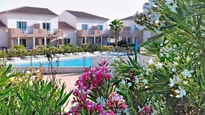 A hotel with a swimming pool, multiple balconies, and lush greenery.