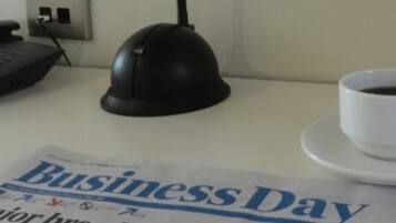 A business newspaper on a table with a coffee cup and a telephone.