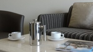 Et moderne værelse med en sort læderlænestol, en stribet sofa og et lille bord med to hvide kopper og en sølvkanne.