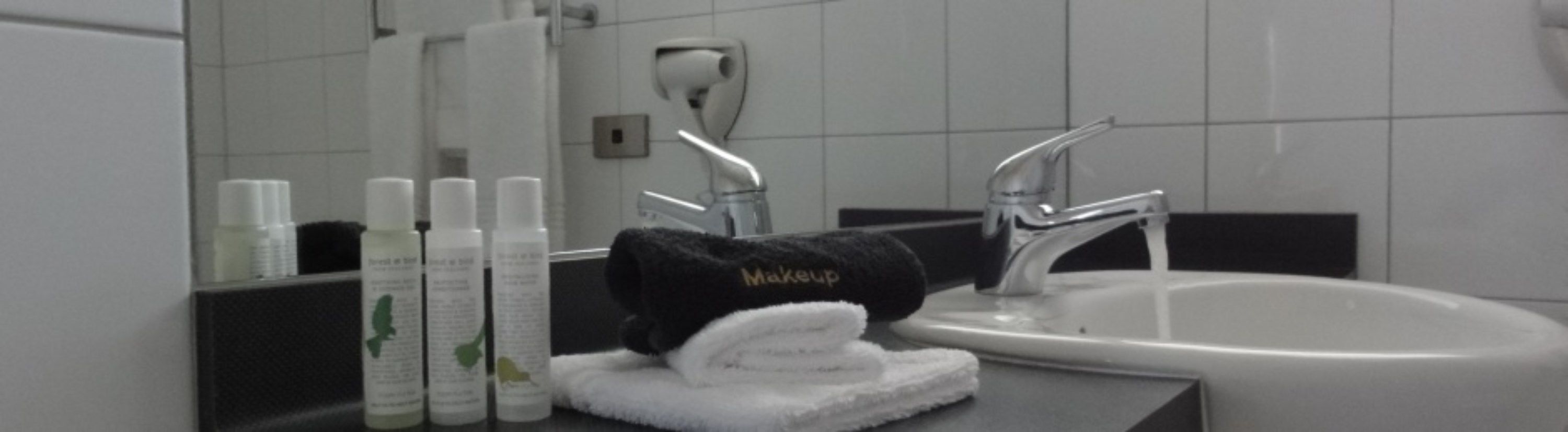 Un baño con lavamanos, espejo y artículos de aseo.