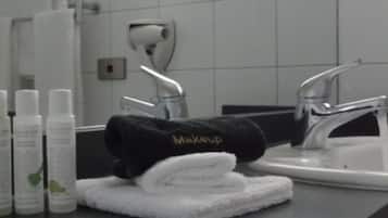 Un baño con lavamanos, espejo y artículos de aseo.