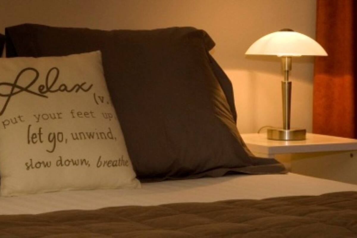 A bed with two nightstands, each with a lamp, and a pillow with a motivational quote.