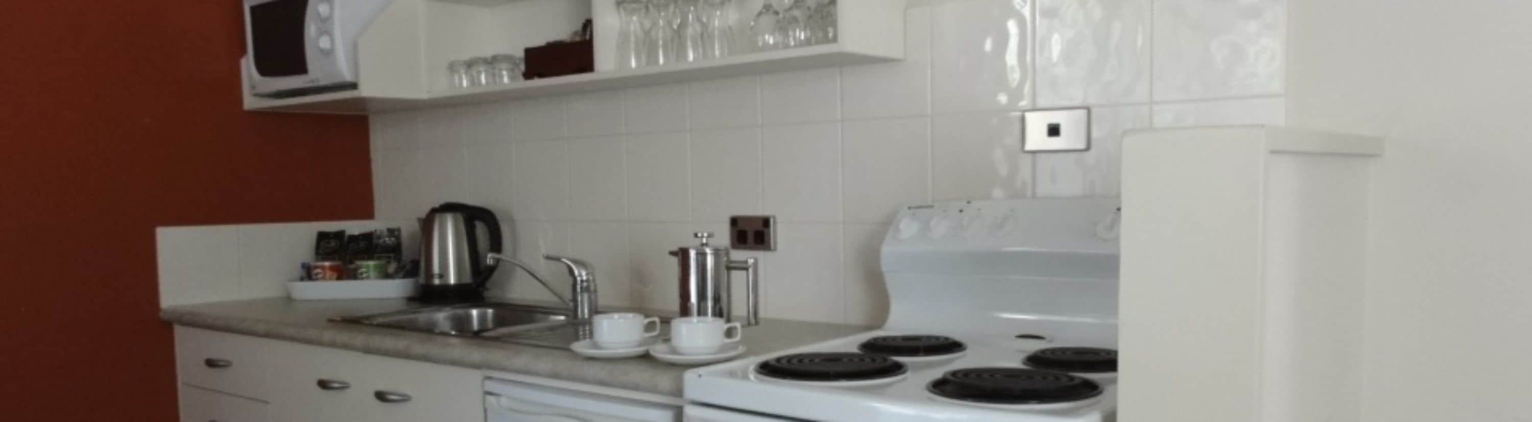 Cozinha com fogão, pia e cafeteira.