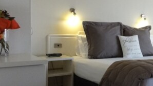 Et hotelværelse med seng, sengeborde, et skrivebord og en stol.