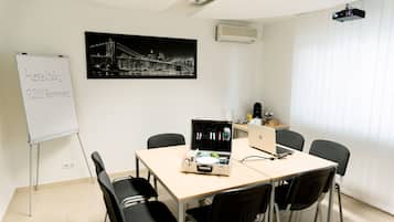 A conference room with a whiteboard, a projector, a laptop, and a table with chairs.