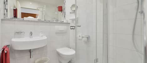 A modern bathroom with a white sink, toilet, and shower.