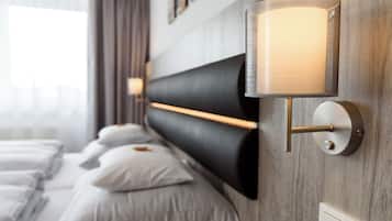 A modern hotel room with a large bed, a headboard with integrated lighting, and a wall-mounted lamp.