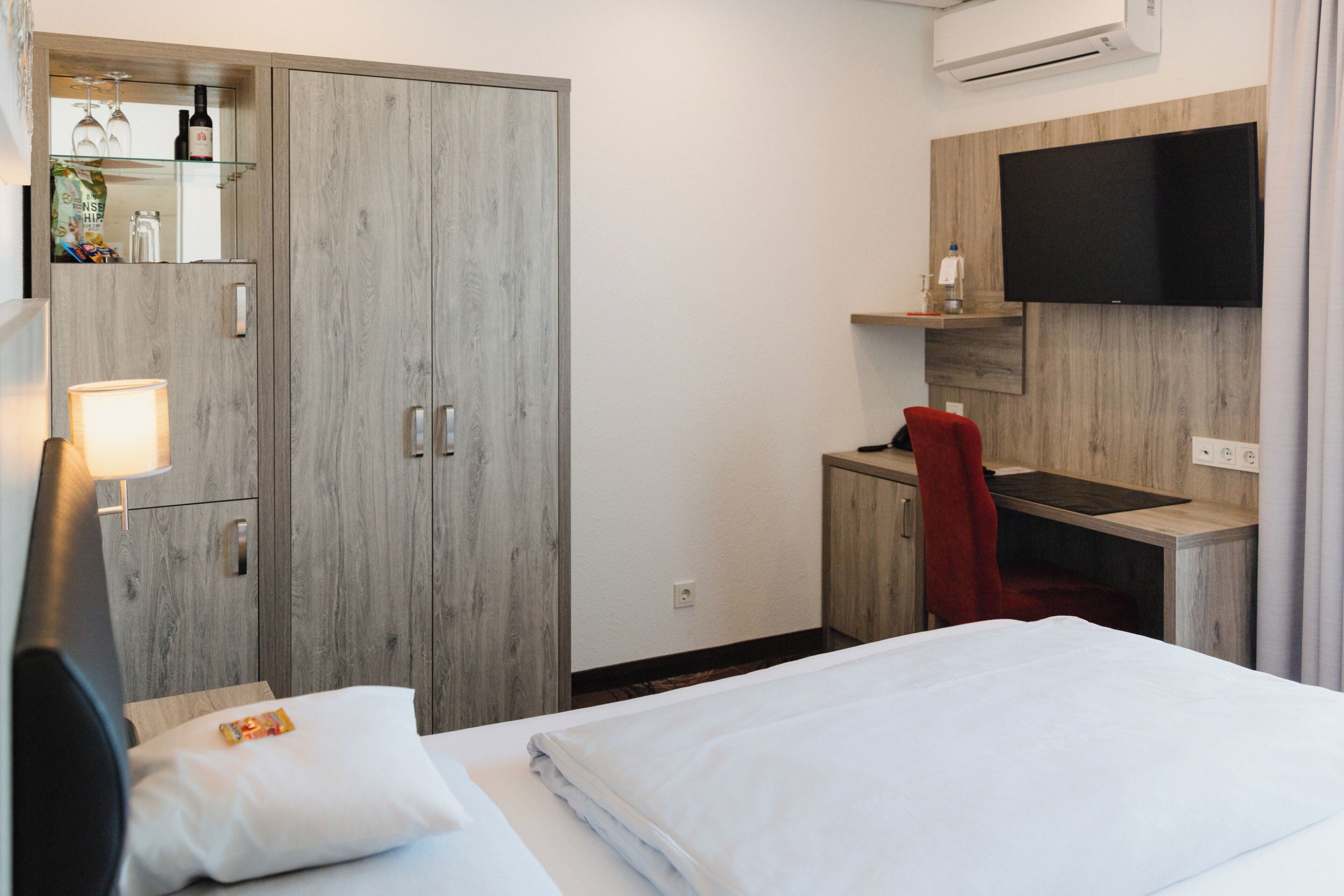 Ein Hotelzimmer mit einem Bett, einem Schreibtisch, einem Fernseher und einem Kleiderschrank.