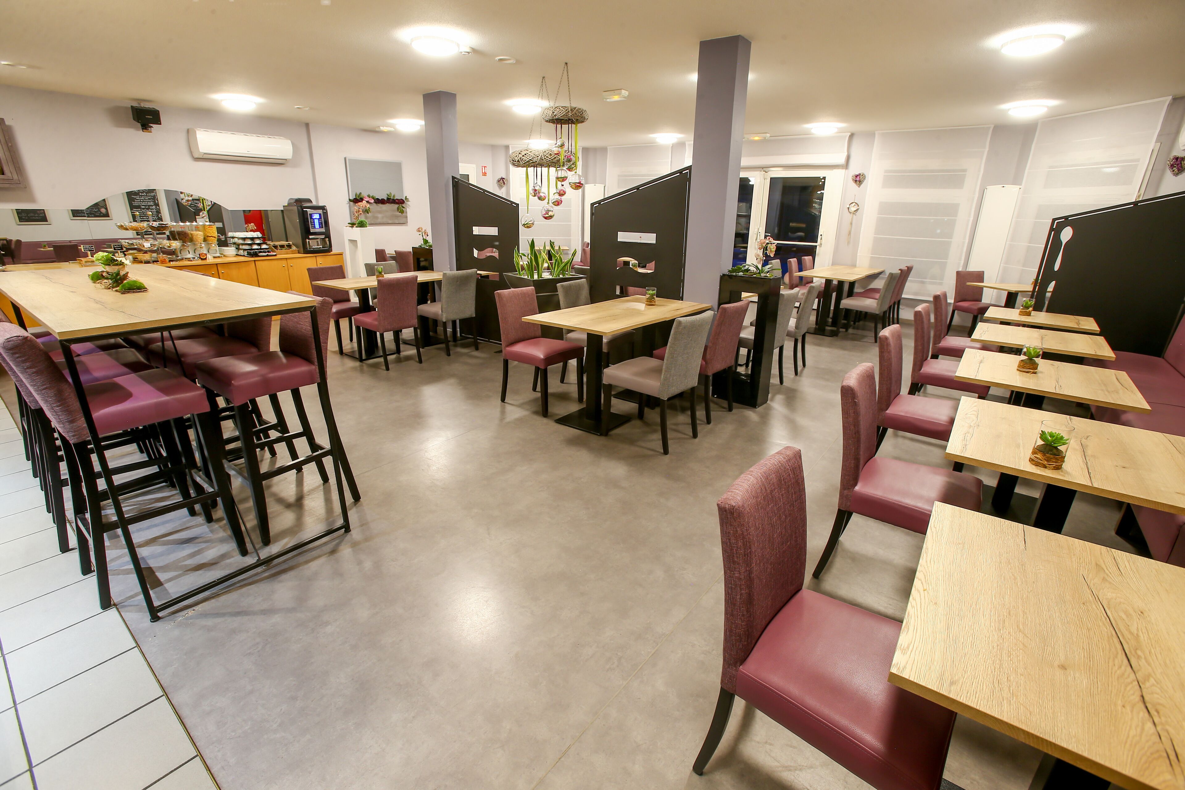 Un restaurante moderno con varias zonas de estar, incluyendo mesas y cabinas, y una cocina a la vista.