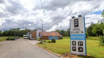 A hotel entrance sign with amenities and a building in the background.