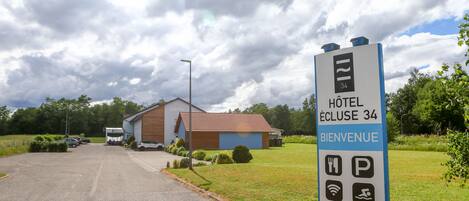 A hotel entrance sign with amenities and a building in the background.