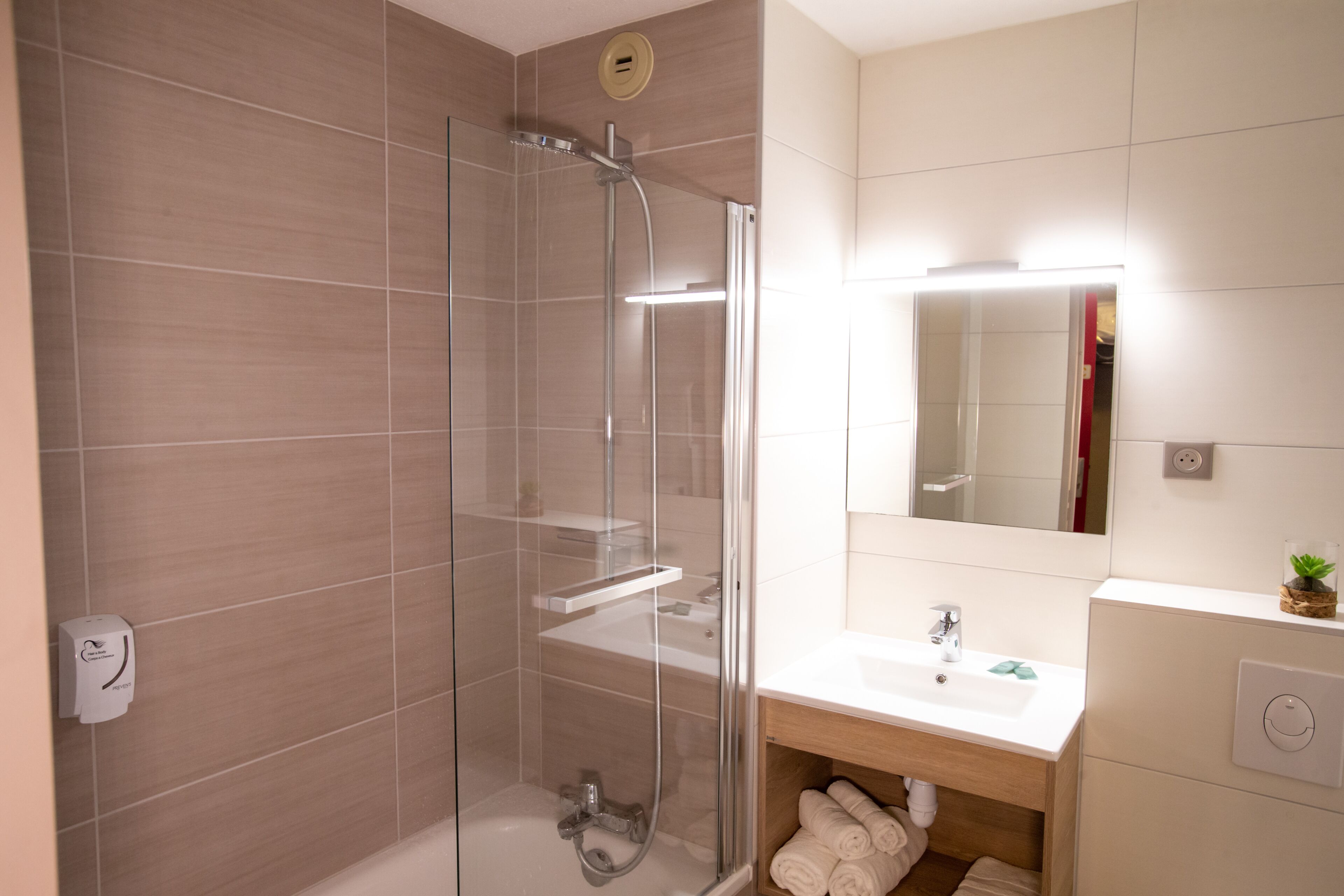 A modern bathroom with a glass-enclosed shower, a sink, and a mirror.
