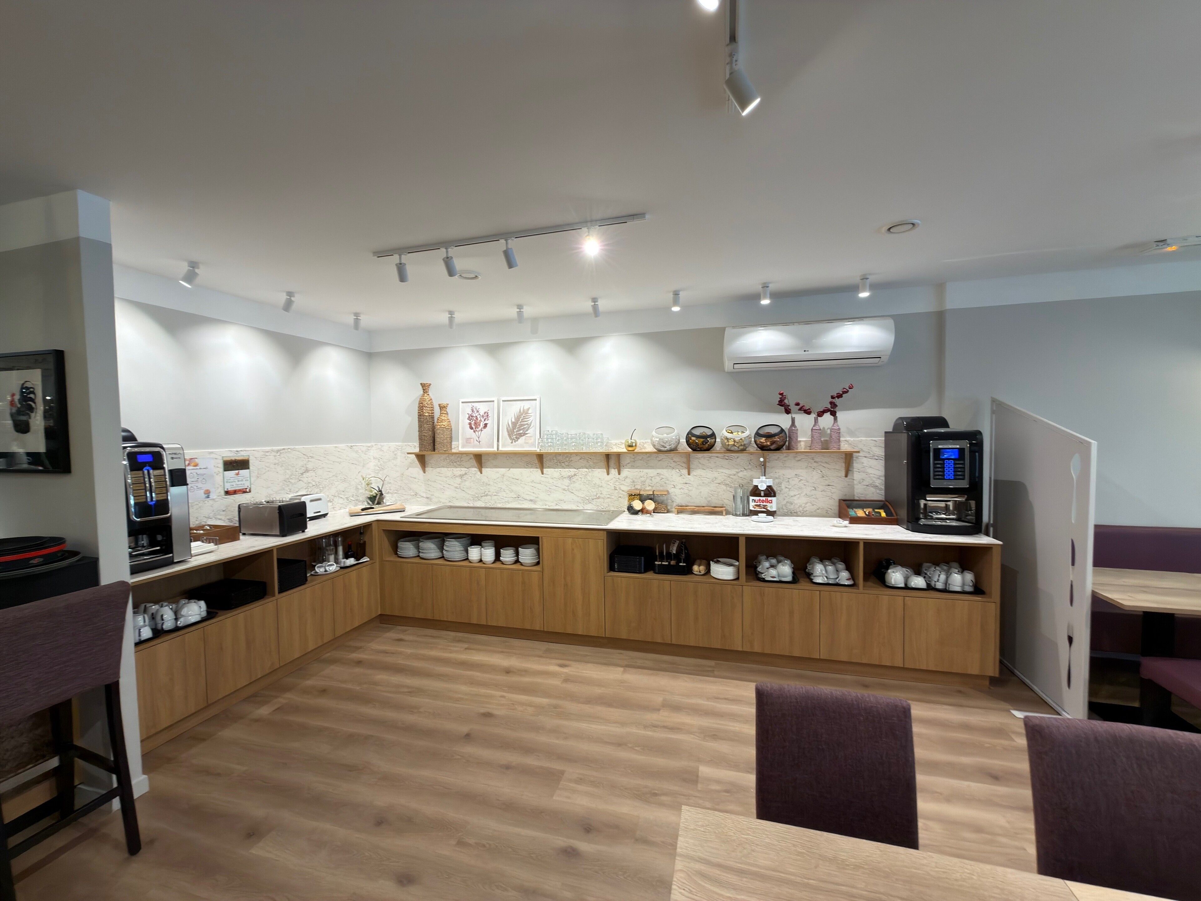 Una cocina moderna con encimera de mármol, armarios de madera y una cafetera.