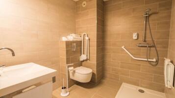 Un baño moderno con lavamanos, inodoro y ducha.