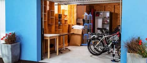 Un garaje con pared azul, estanterías de madera, una mesa y bicicletas.