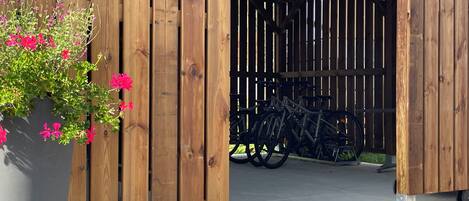 Une structure en bois avec un porte-vélo et un pot de fleurs contenant des fleurs roses.