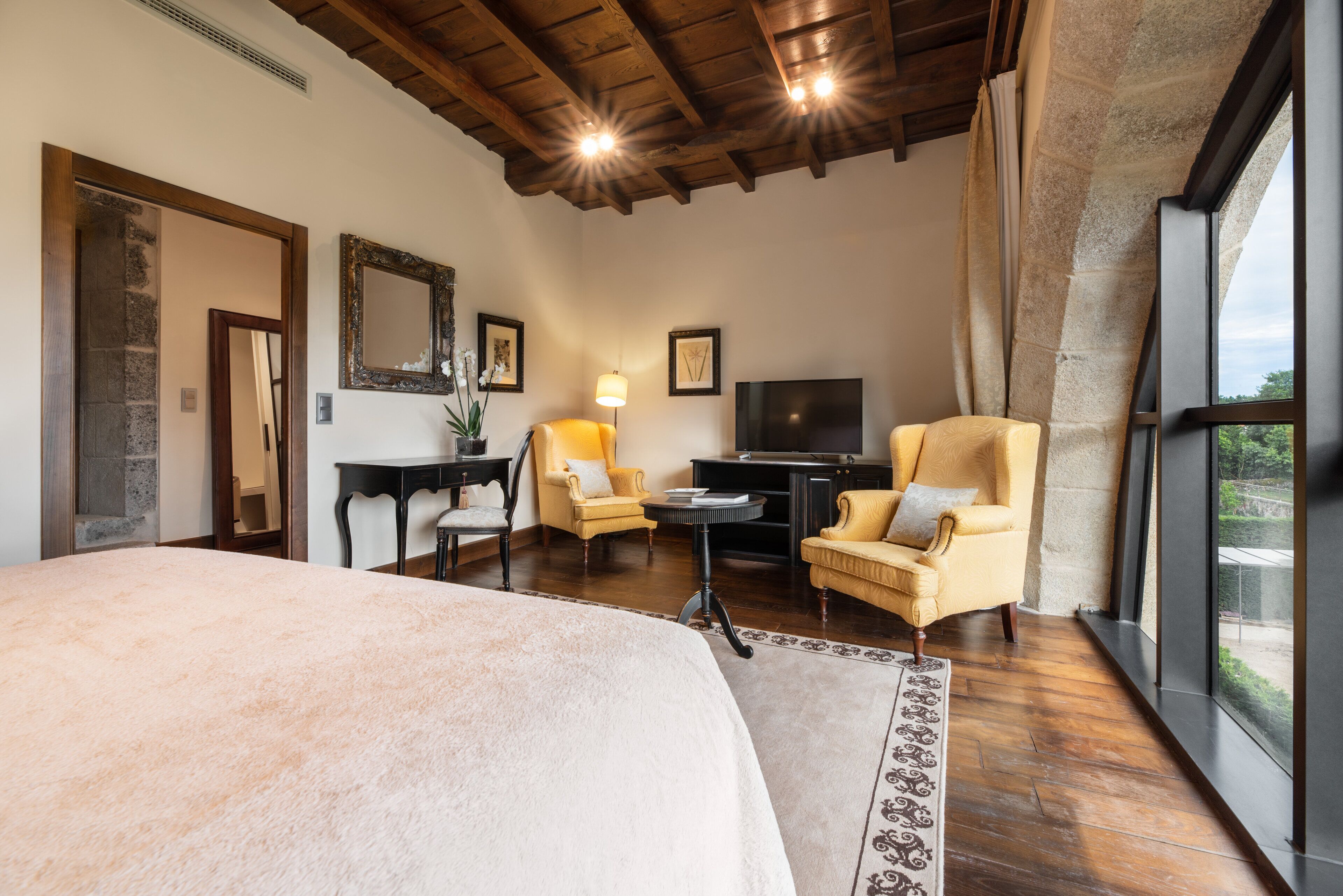 A spacious bedroom with a large bed, a television, and two armchairs.