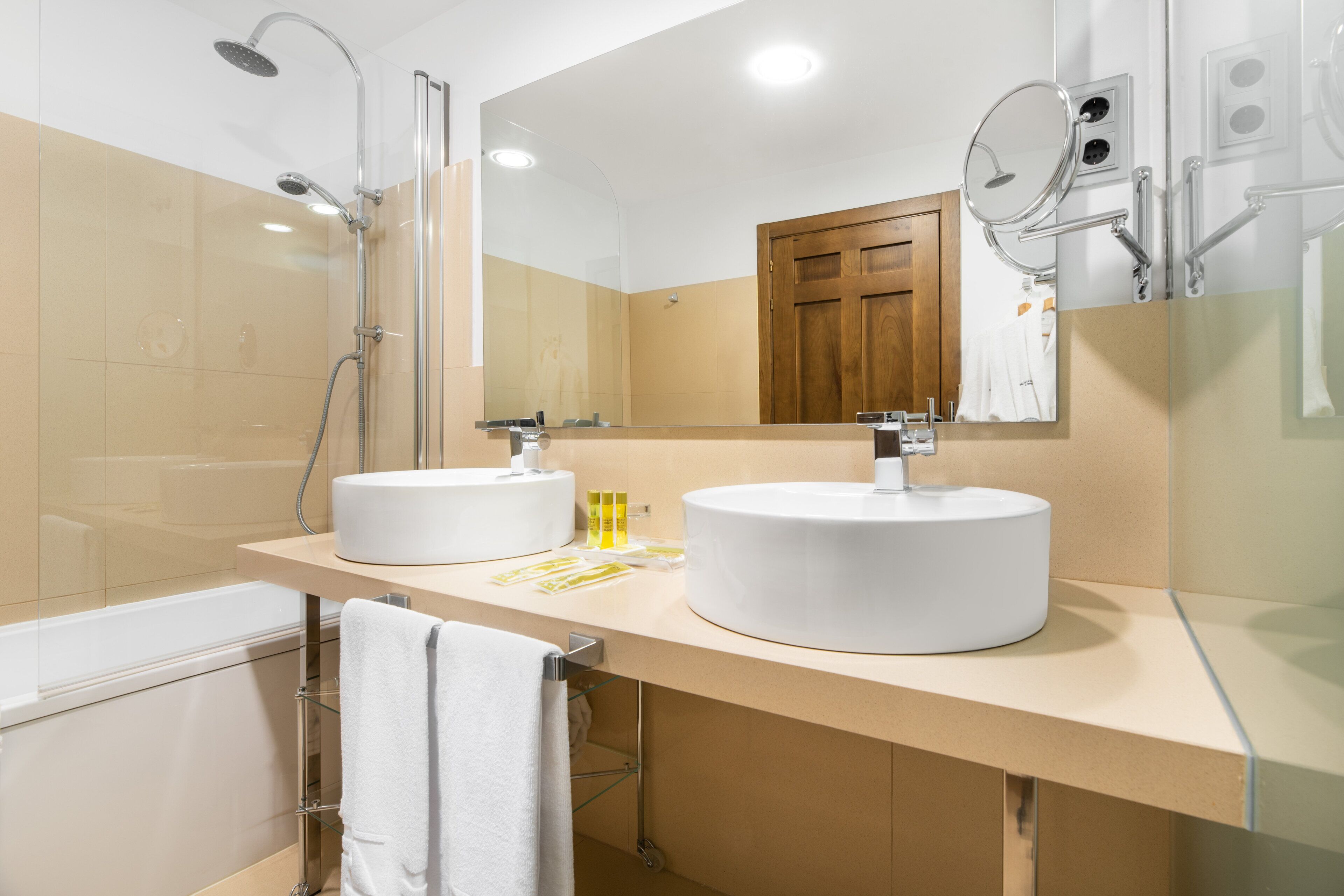 A modern bathroom with two sinks, a shower, and a large mirror.