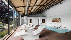 A spa area with a pool, reclining chairs, and artwork on the walls.