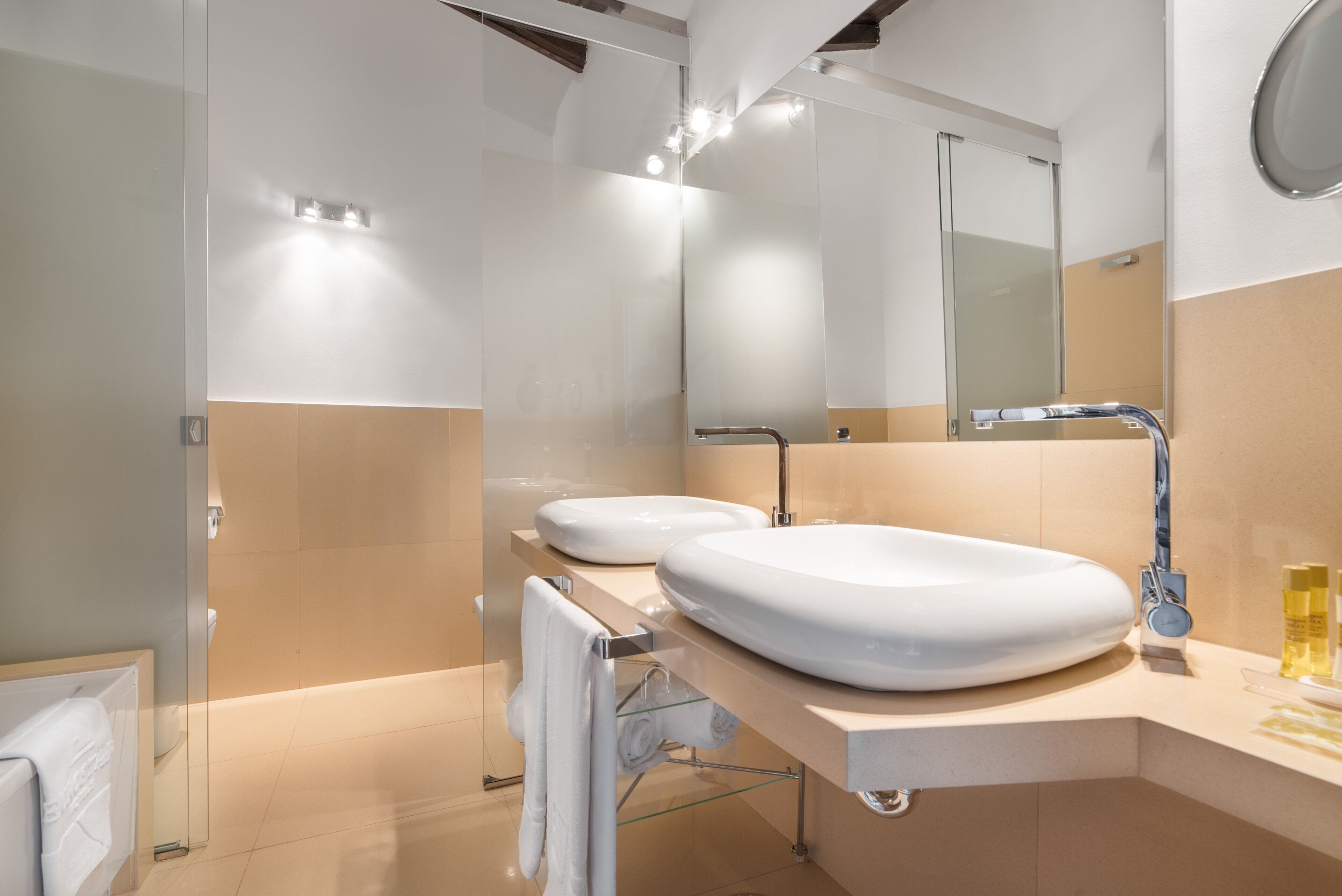 Un baño moderno con dos lavamanos, un espejo grande y una cabina de ducha de vidrio.