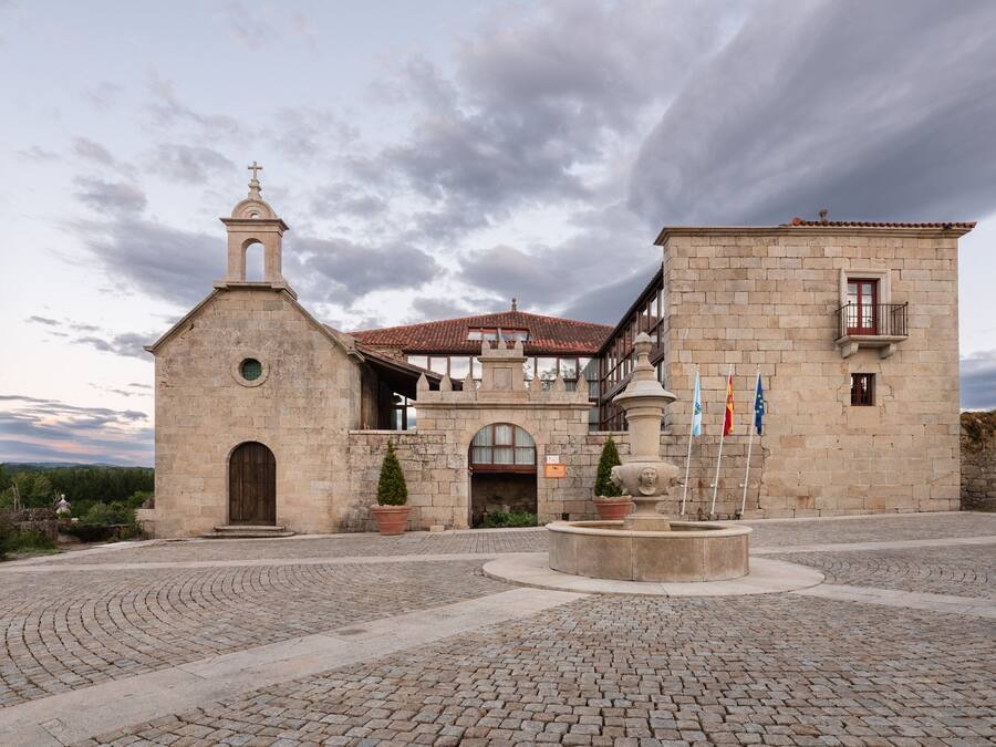 Un edificio histórico con una iglesia, una fuente y banderas.