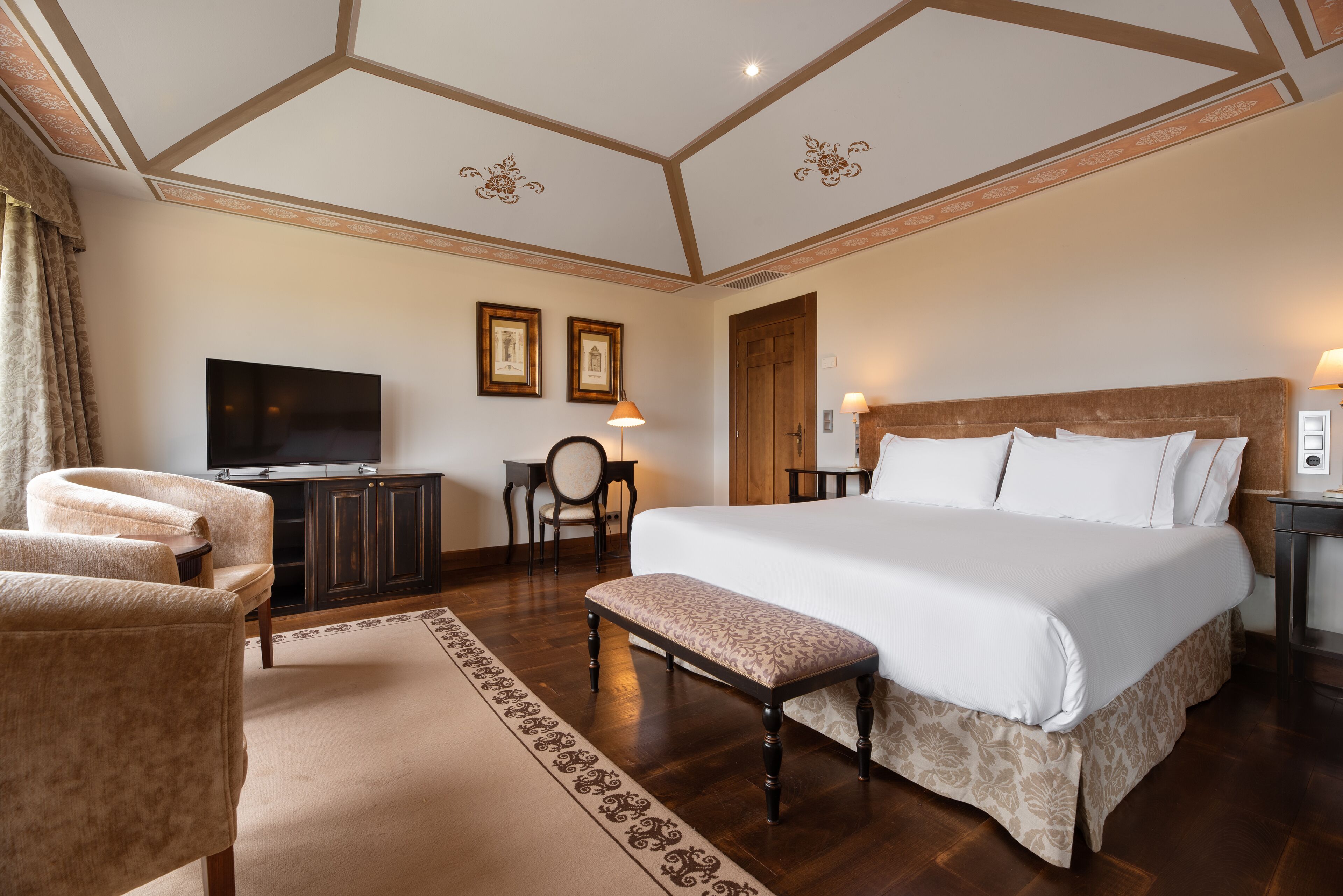A hotel room with a large bed, a television, a desk, and a chair.