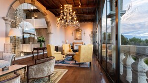 A spacious lobby with a chandelier, comfortable seating, and a large arched doorway.