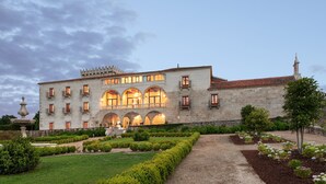 A large stone building with multiple arches and a well-maintained garden.
