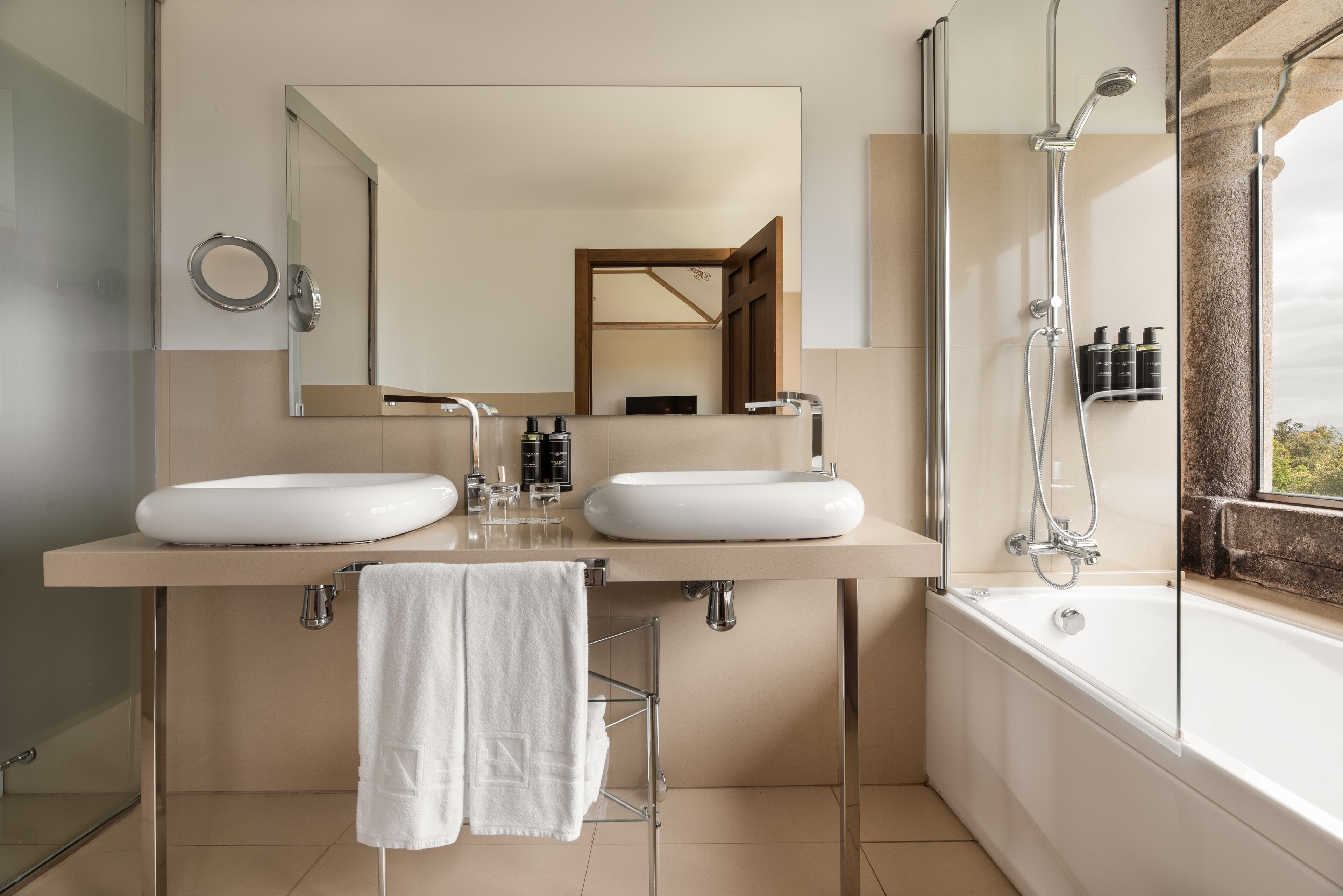 Une salle de bain moderne avec deux lavabos, un grand miroir, une douche et une baignoire.