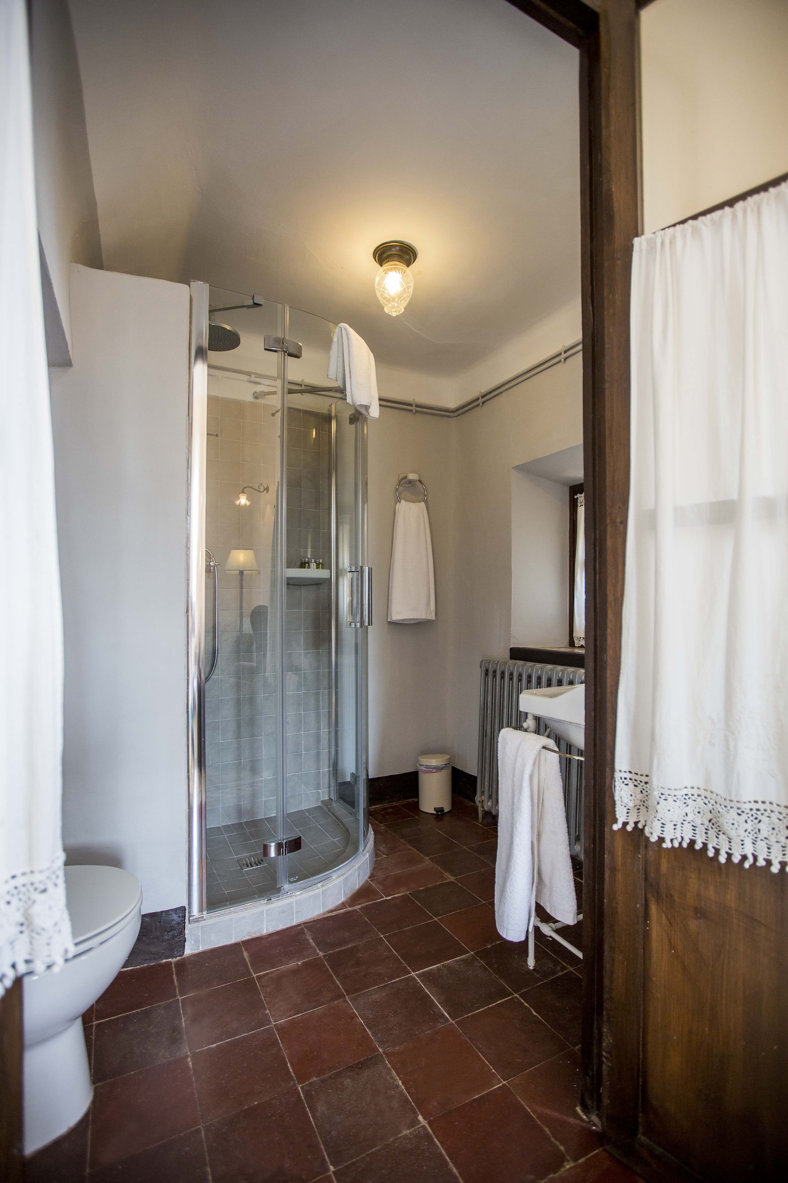 Un ba ño con ducha de vidrio, inodoro, lavamanos y espejo.