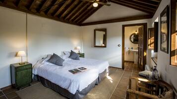 A bedroom with a large bed, bedside tables, a wooden ceiling, and a mirror on the wall.