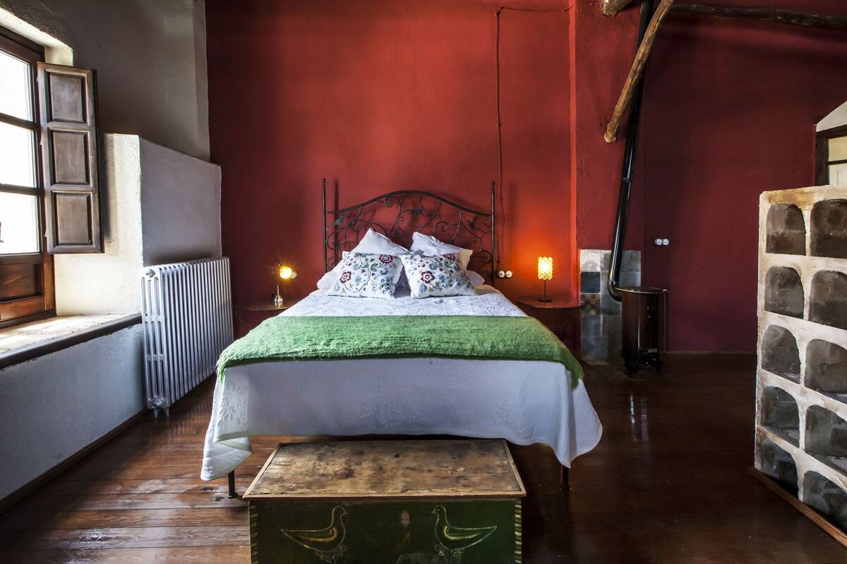 A room with a bed, a radiator, a window, and a stone wall.