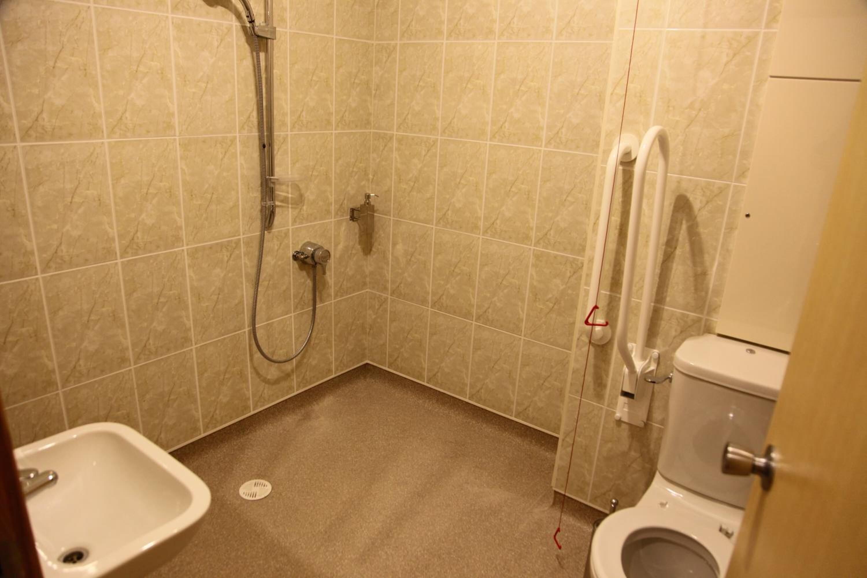 A small bathroom with a toilet, sink, and shower.