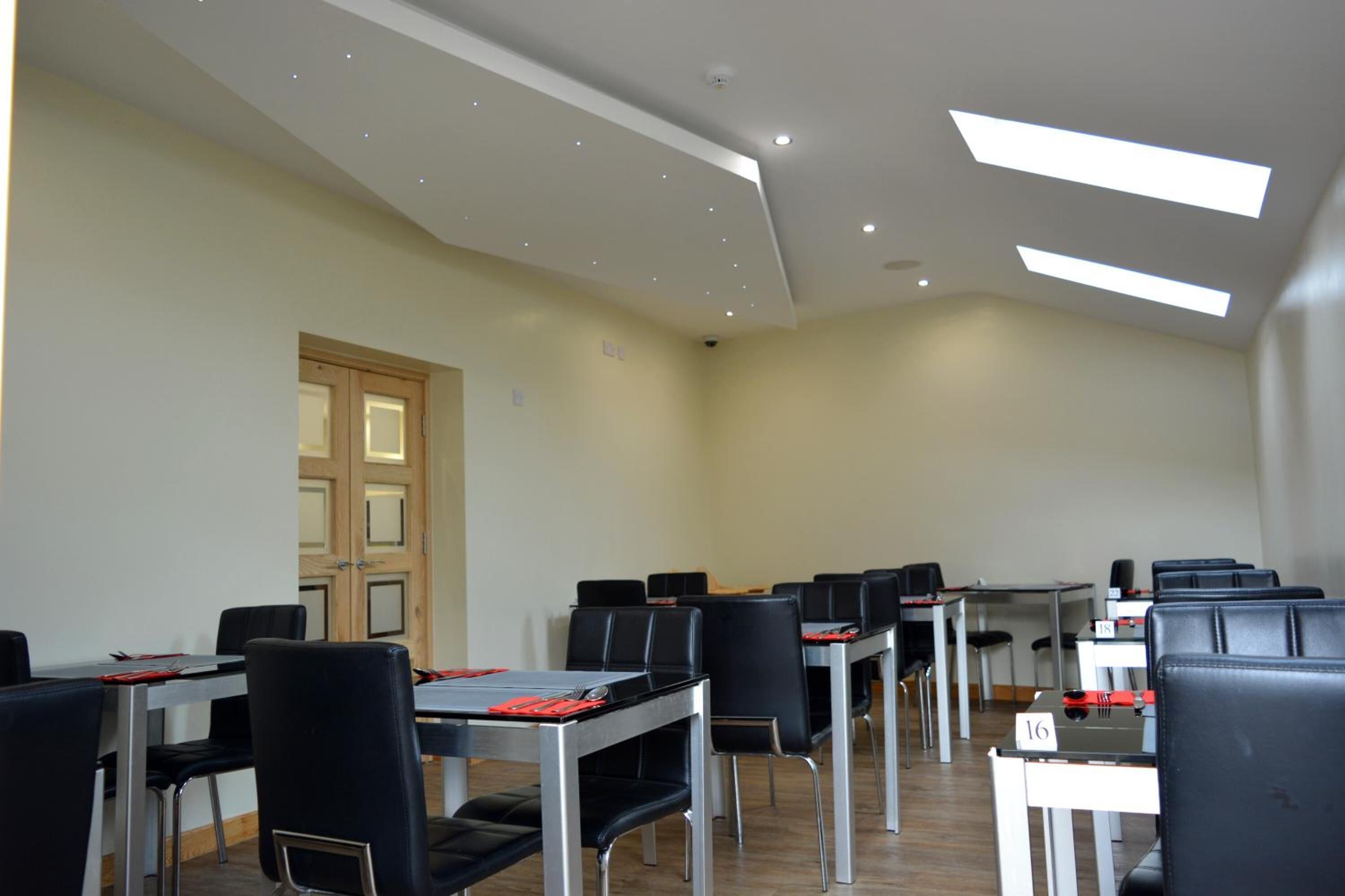A conference room with tables and chairs, a door, and skylights.