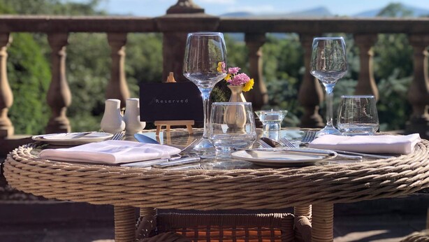 A wicker table set for a meal with a view of trees and mountains in the background. - Peterstone Court (Brecon)