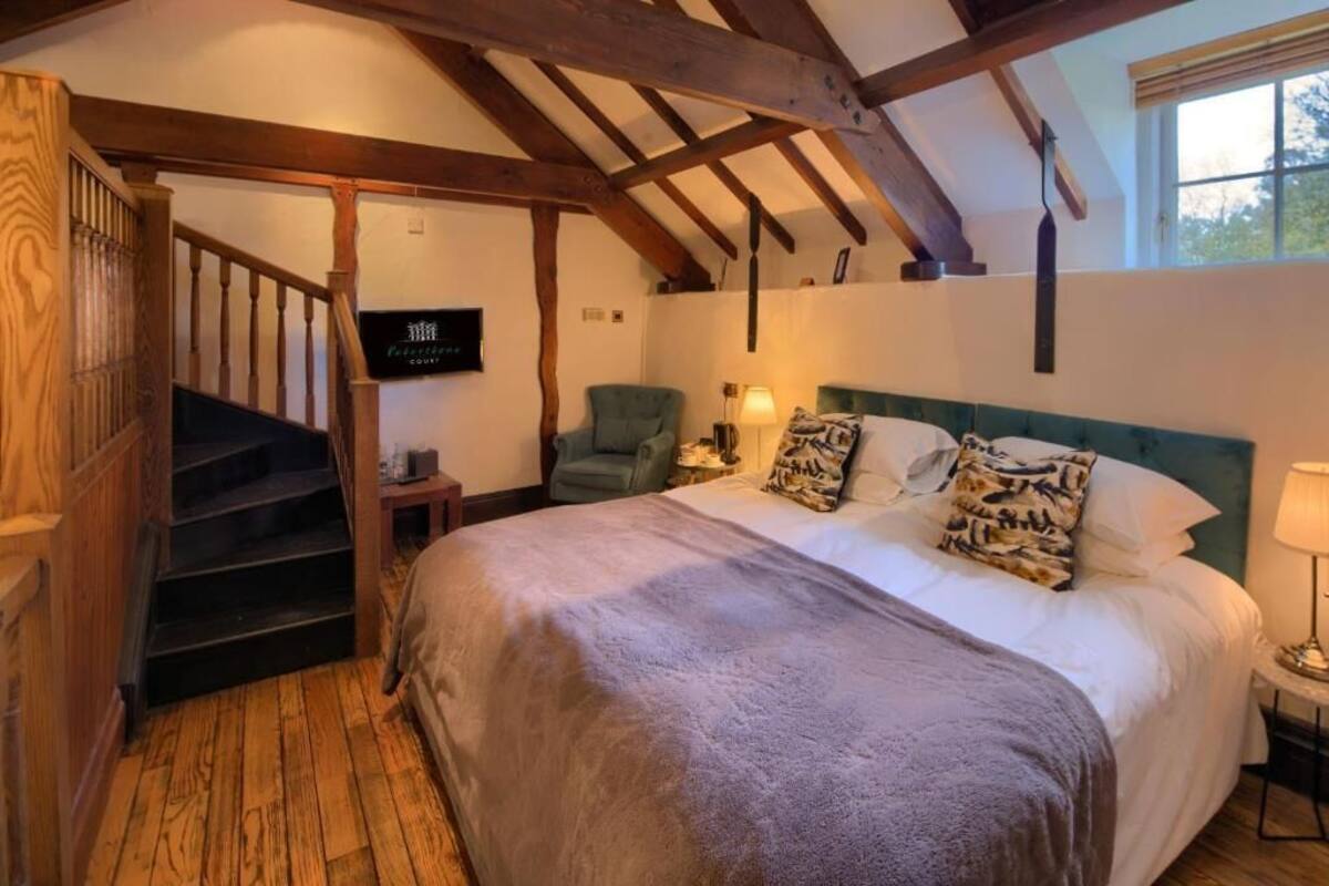 Quarto com uma cama grande, uma cadeira, uma televisão e uma escada.