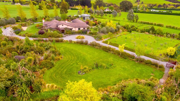 A large house with a well-maintained lawn and garden, surrounded by rolling hills and a clear sky. - The Summit Lodge (Gladstone)