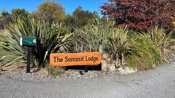 Señal de 'The Summit Lodge' con un buzón con el número 4 y diversas plantas al fondo.