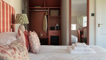 A bedroom with a bed, a bedside table, a mirror, a wardrobe, and a desk with a chair.