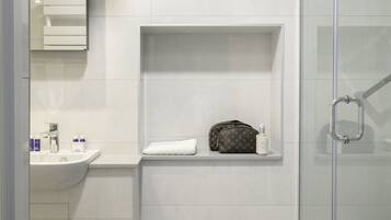 Une salle de bain moderne avec une douche à parois de verre, un meuble-lavabo avec un miroir et une étagère pour les articles de toilette.