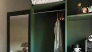 A cozy room with a bed, a seating area with a sofa and armchairs, a coffee table, and a shelf with a kettle and cups. - Teach de Broc (Ballybunion)