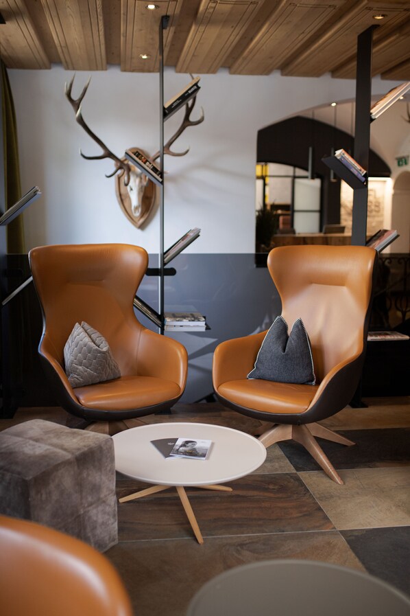 Un interior moderno con dos sillones de cuero, una mesa redonda y un cráneo de ciervo decorativo en la pared.