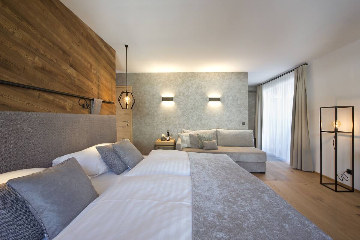 Une chambre d’hôtel moderne avec un grand lit, un canapé, une table de chevet et une lampe.