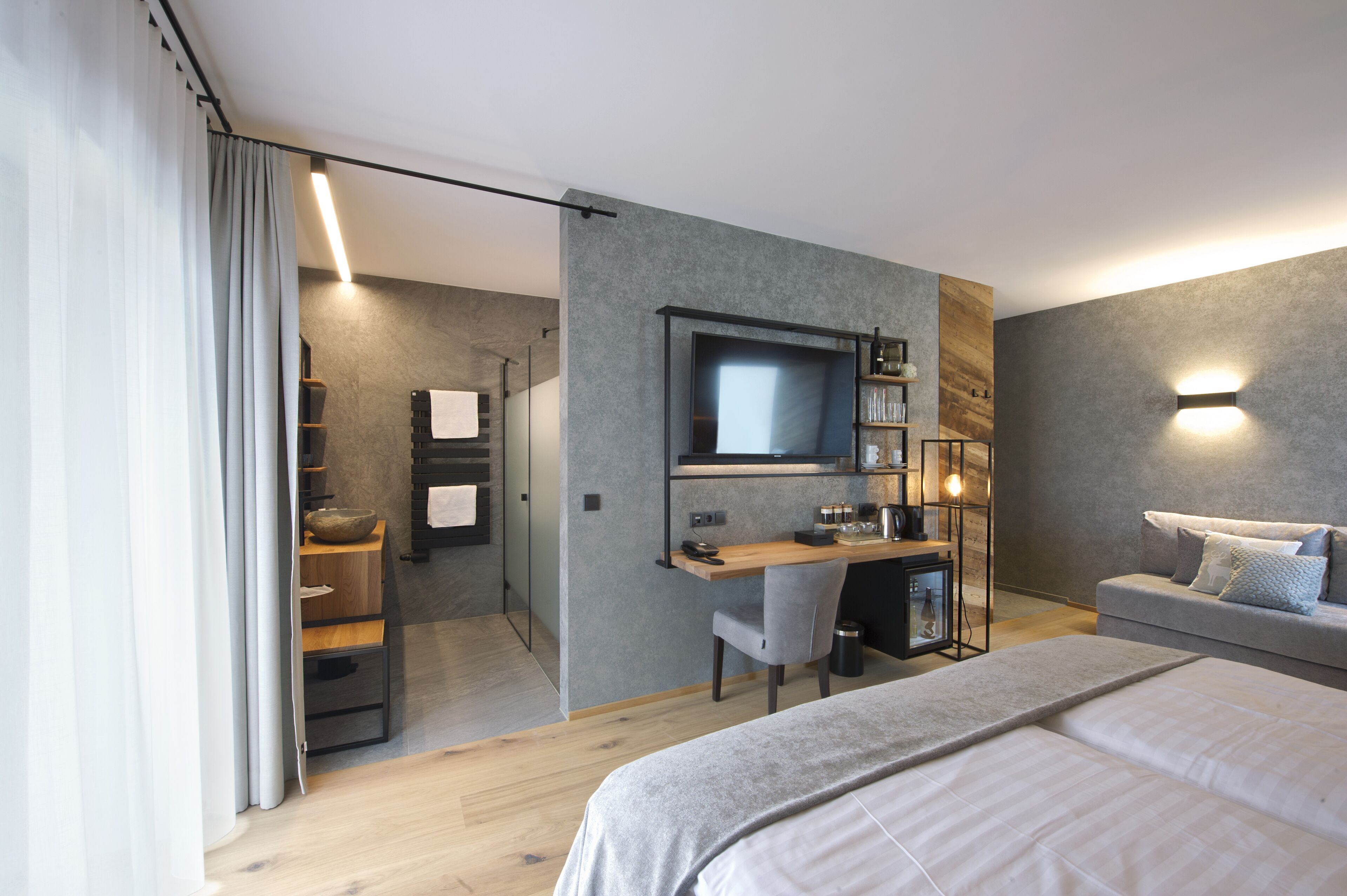 A modern bedroom with a large bed, a desk, and a TV.