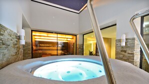 Un jacuzzi con una pared de piedra y un banco de madera al fondo.