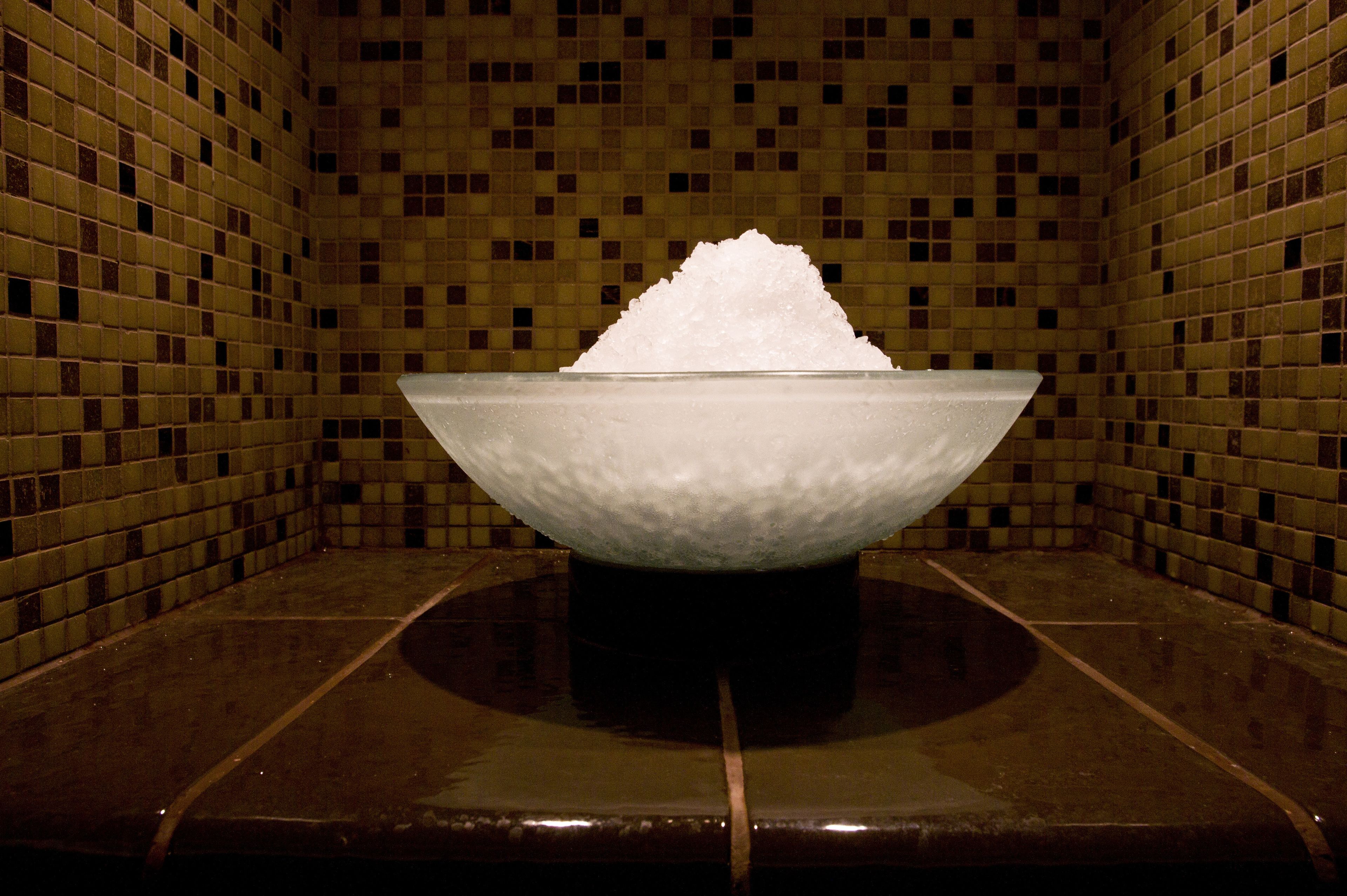 A tiled room with a central glass bowl containing a white substance.